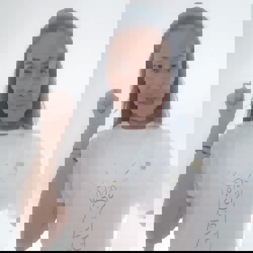 woman with long brown hair holding fist in the air and wearing white t-shirt with cat paw design