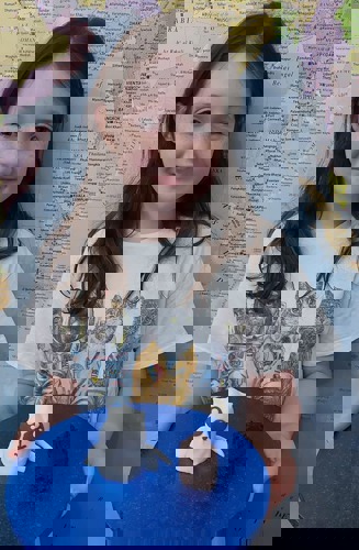 young brunette girl holding plate with rocketship cat cake on it